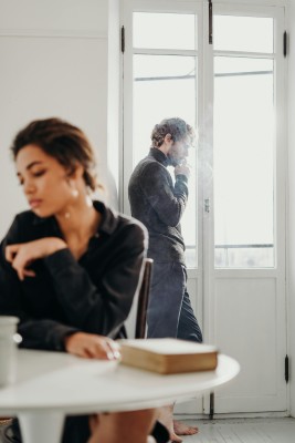 A couple experiencing tension and introspection indoors with a bright window.